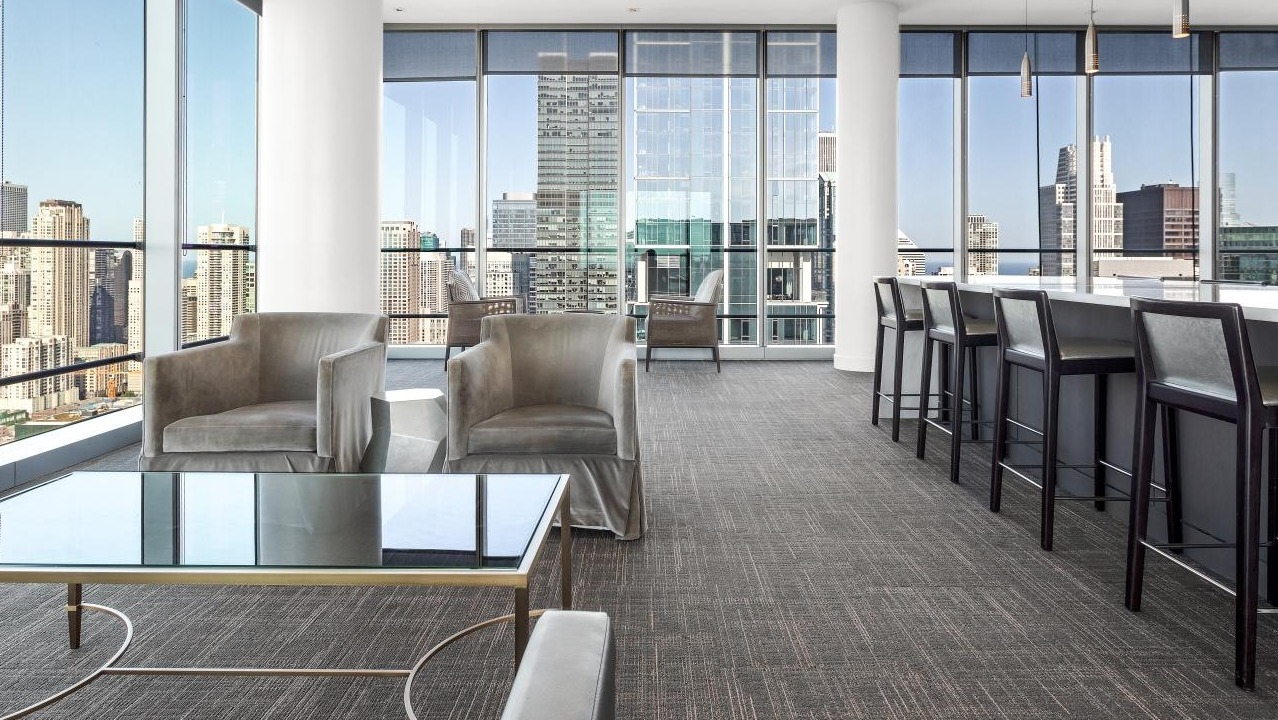 Residents’ lounge at Wolf Point West apartments in Chicago with bar seating, modern furniture, and expansive city views