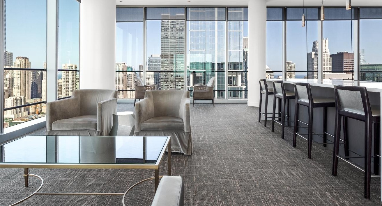 Residents’ lounge at Wolf Point West apartments in Chicago with bar seating, modern furniture, and expansive city views