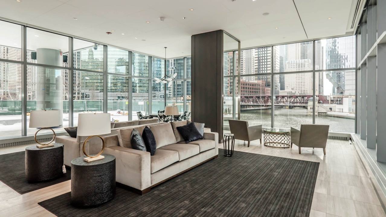 Stylish river lounge at Wolf Point West apartments in Chicago featuring modern furniture, floor-to-ceiling windows, and river views