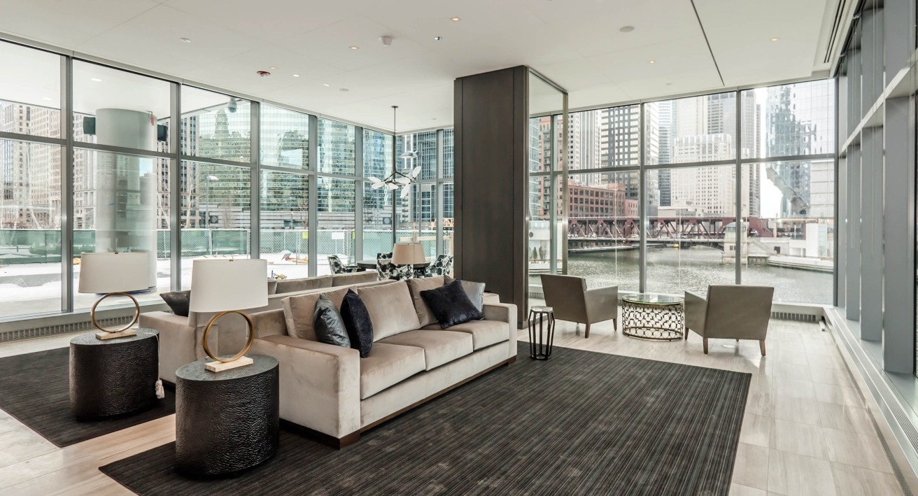 Stylish river lounge at Wolf Point West apartments in Chicago featuring modern furniture, floor-to-ceiling windows, and river views