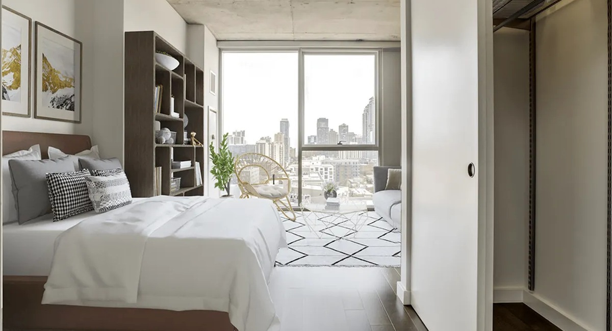 Contemporary bedroom with a bed, bookshelf, city views, and an open closet at Xavier Apartments in Chicago
