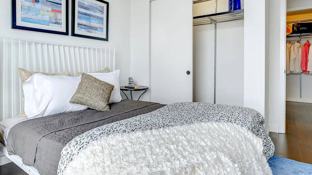Modern bedroom with a comfortable bed, artistic wall decor, and a spacious walk-in closet at Xavier Apartments in Chicago