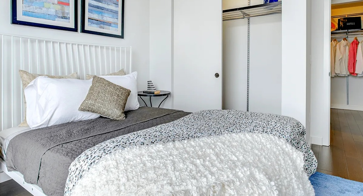 Modern bedroom with a comfortable bed, artistic wall decor, and a spacious walk-in closet at Xavier Apartments in Chicago