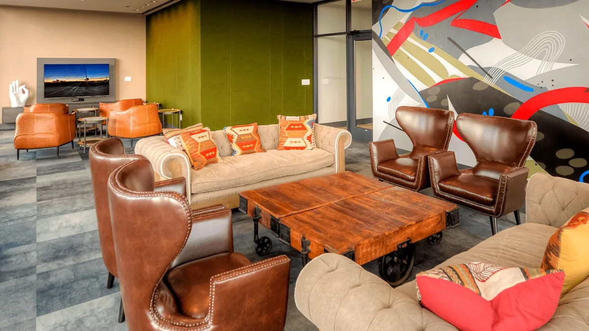Vibrant resident lounge with abstract wall art, plush seating, and a TV for entertainment at Xavier Apartments in Chicago