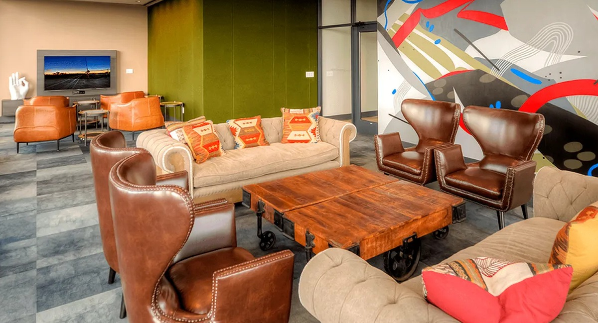 Vibrant resident lounge with abstract wall art, plush seating, and a TV for entertainment at Xavier Apartments in Chicago