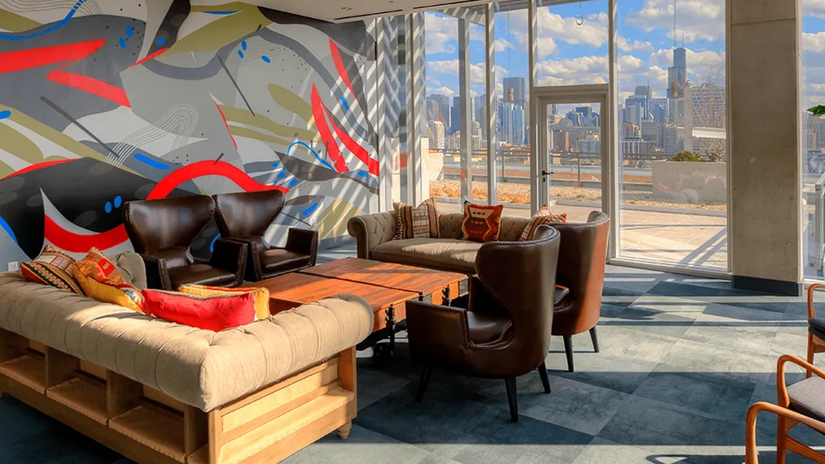 Vibrant resident lounge with abstract wall art, comfortable seating, and large windows offering city views at Xavier Apartments in Chicago