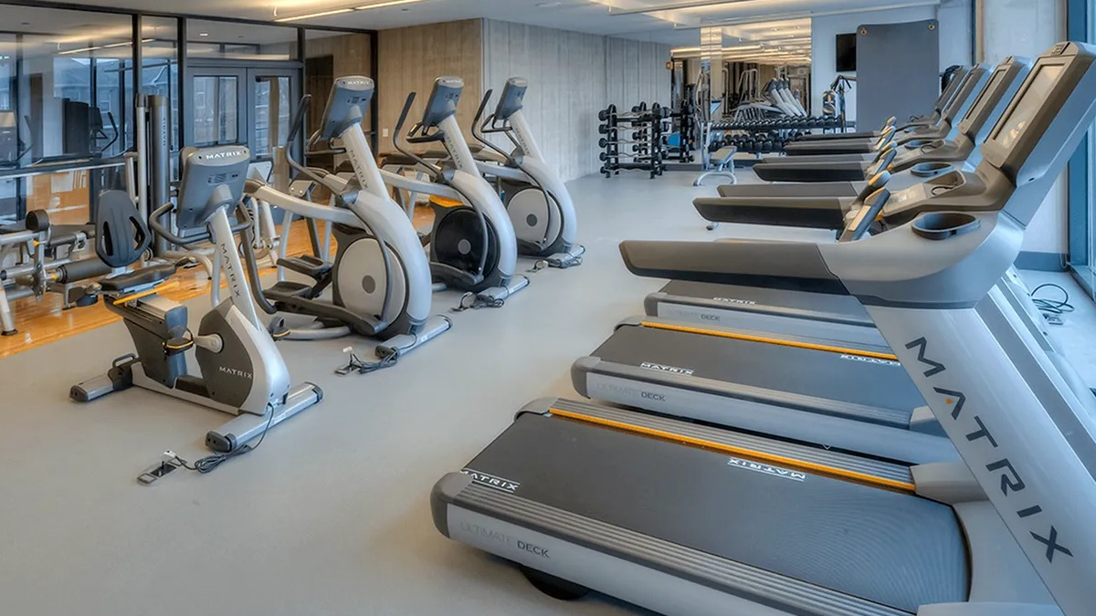 Bright fitness center featuring treadmills, ellipticals, and other cardio equipment with large windows at Xavier Apartments in Chicago