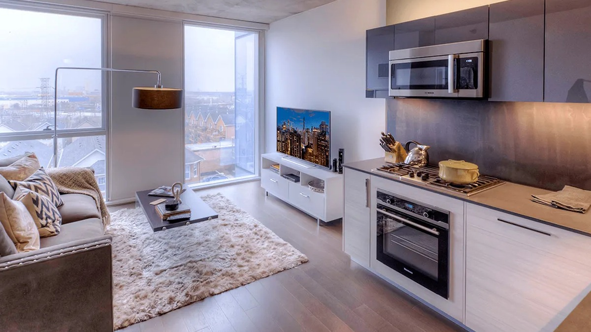Modern kitchen and living room combo with a cozy sofa, area rug, and city views at Xavier Apartments in Chicago