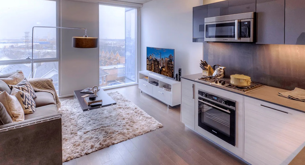 Modern kitchen and living room combo with a cozy sofa, area rug, and city views at Xavier Apartments in Chicago