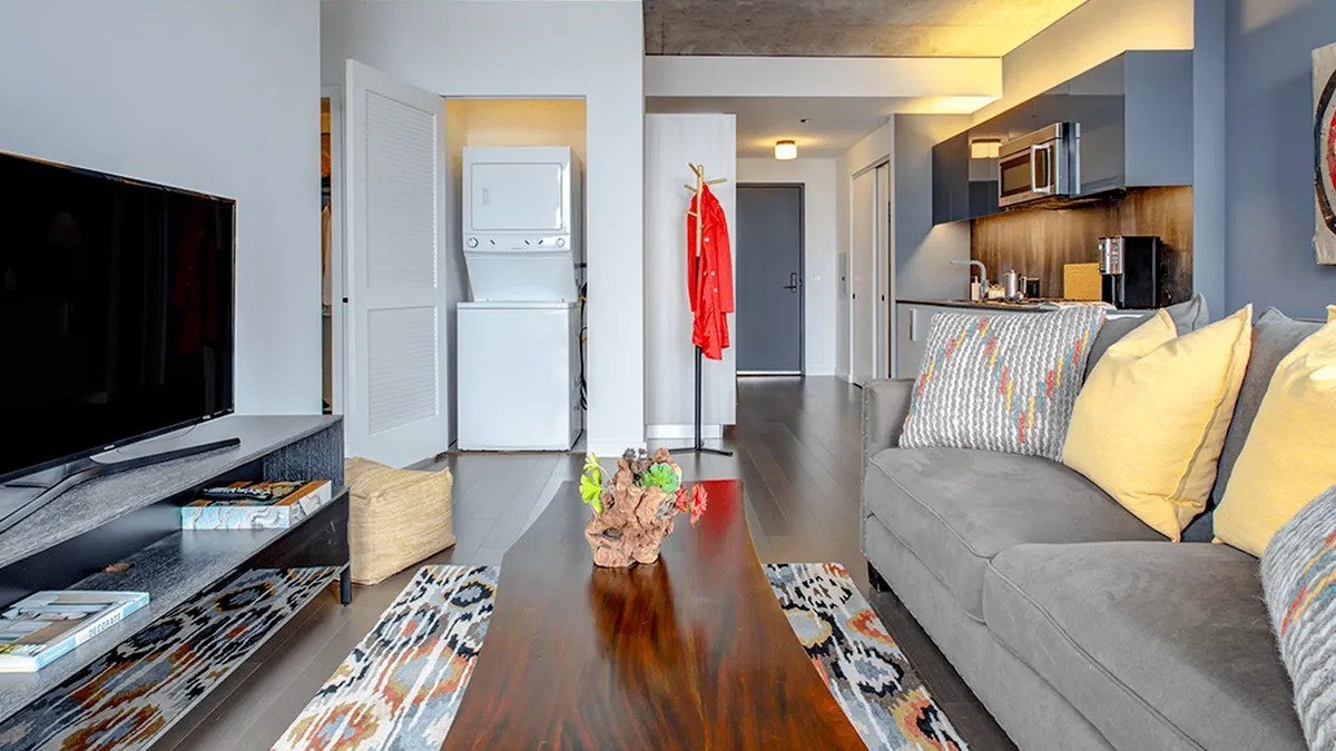 Stylish living room with a sofa, coffee table, and visible in-unit laundry appliances in the hallway at Xavier Apartments in Chicago