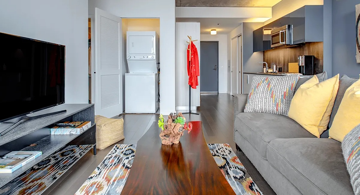 Stylish living room with a sofa, coffee table, and visible in-unit laundry appliances in the hallway at Xavier Apartments in Chicago