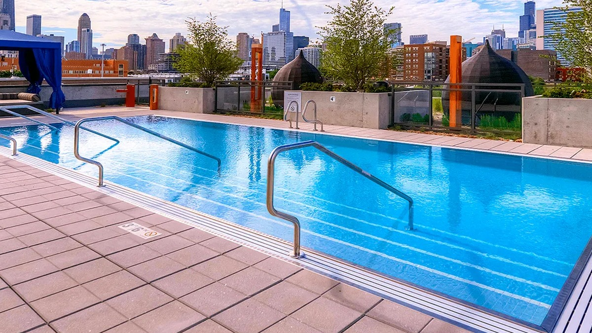 Sparkling outdoor swimming pool with handrails and a stunning Chicago skyline backdrop at Xavier Apartments in Chicago