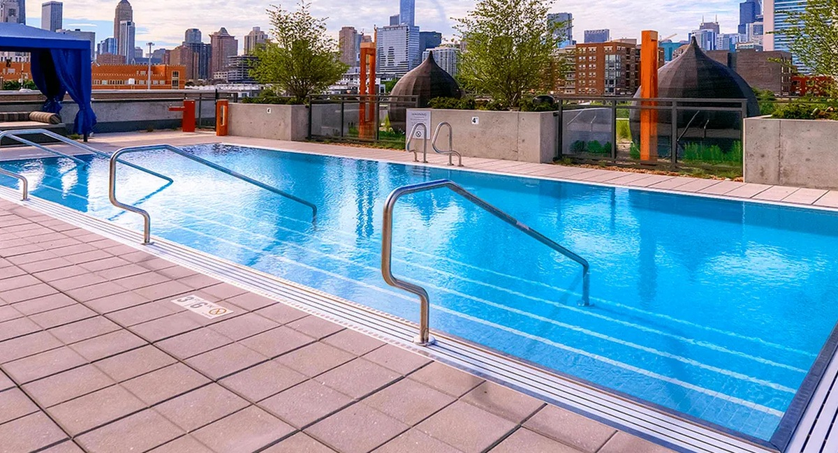 Sparkling outdoor swimming pool with handrails and a stunning Chicago skyline backdrop at Xavier Apartments in Chicago