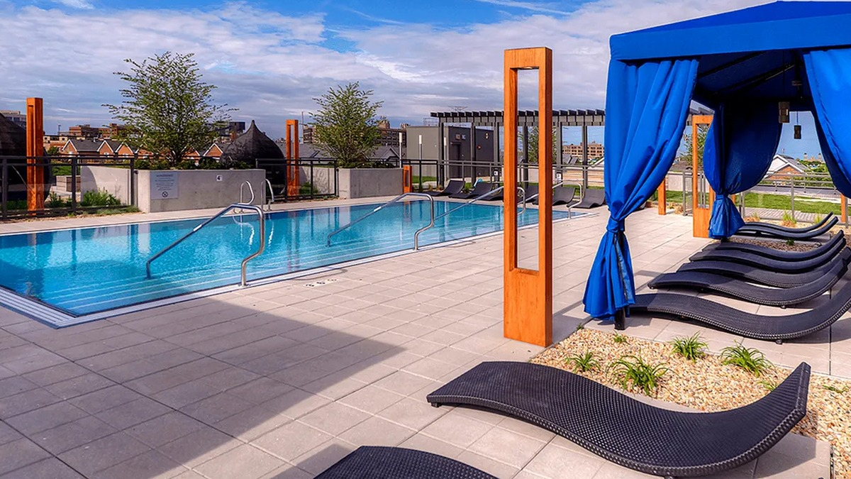 Resort-style outdoor pool area featuring elegant cabanas, sun loungers, and mature landscaping at Xavier Apartments in Chicago