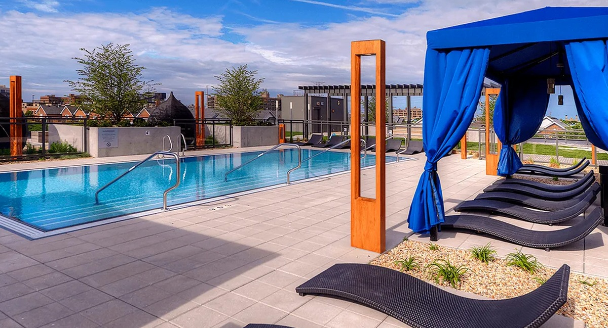 Resort-style outdoor pool area featuring elegant cabanas, sun loungers, and mature landscaping at Xavier Apartments in Chicago