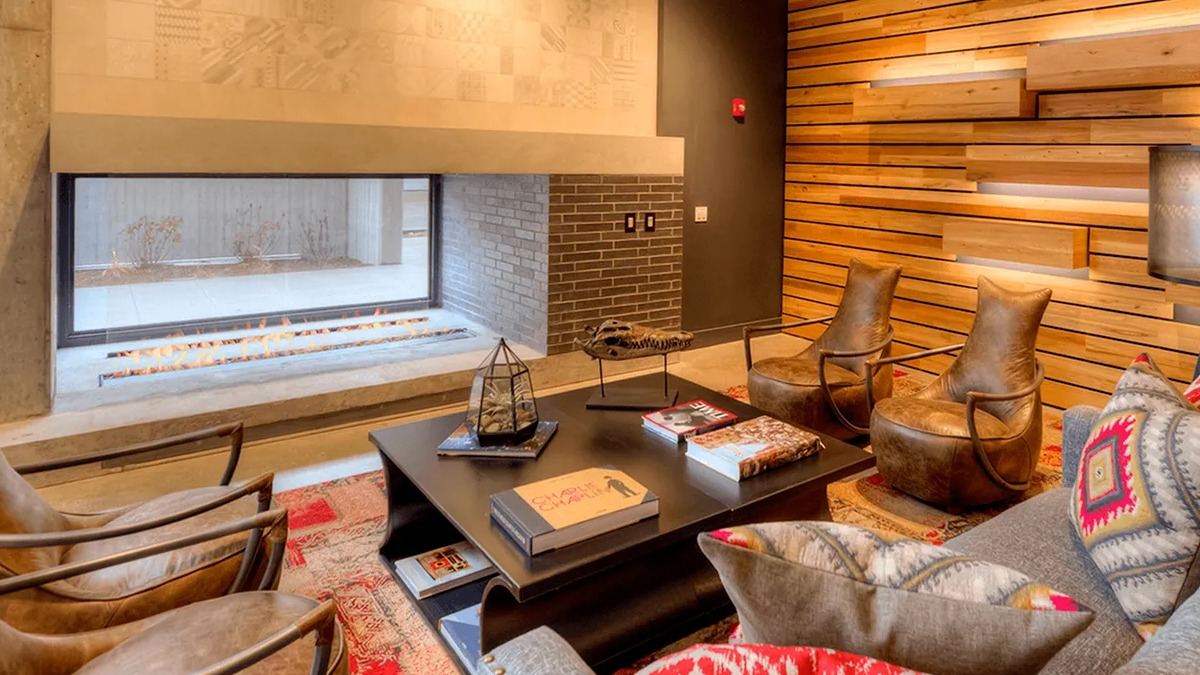 Warm and inviting resident lounge with a modern fireplace, stylish seating, and wood paneling at Xavier Apartments in Chicago