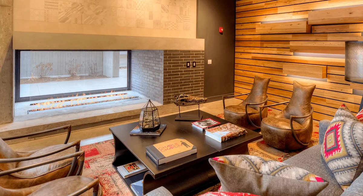 Warm and inviting resident lounge with a modern fireplace, stylish seating, and wood paneling at Xavier Apartments in Chicago