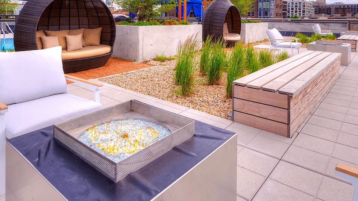 Scenic rooftop lounge area with a cozy fire pit, comfortable seating pods, and city views at Xavier Apartments in Chicago