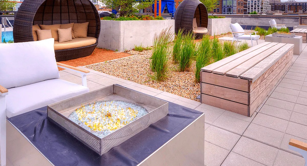 Scenic rooftop lounge area with a cozy fire pit, comfortable seating pods, and city views at Xavier Apartments in Chicago