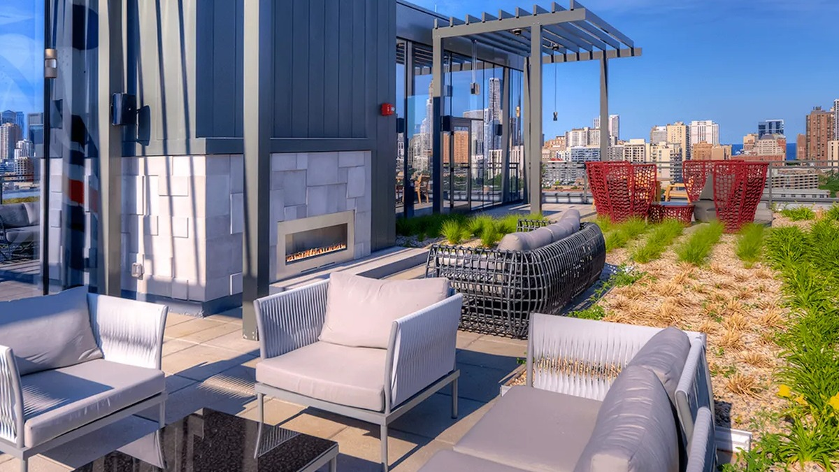 Chic rooftop lounge with modern outdoor furniture, a fireplace, and stunning panoramic city views at Xavier Apartments in Chicago