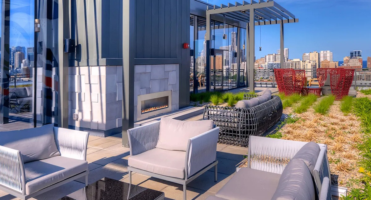 Chic rooftop lounge with modern outdoor furniture, a fireplace, and stunning panoramic city views at Xavier Apartments in Chicago