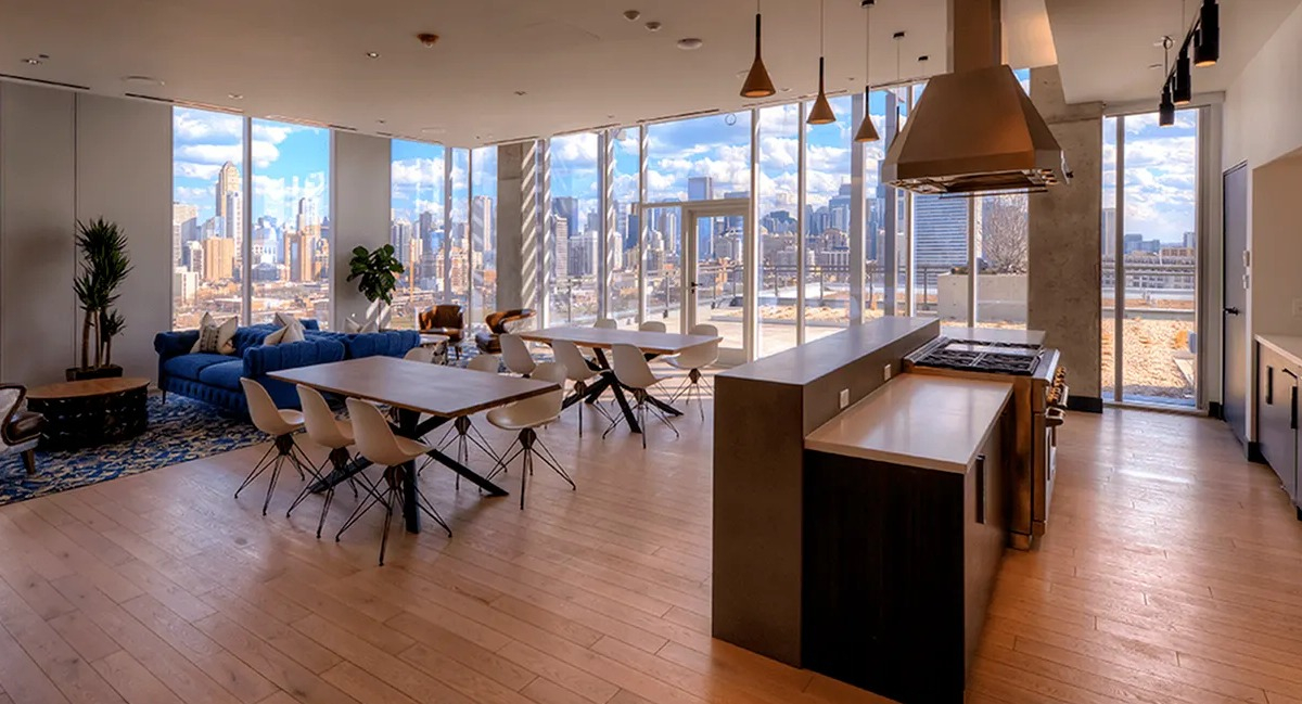 Expansive sky lounge with a full kitchen, dining areas, comfortable seating, and panoramic city views at Xavier Apartments in Chicago